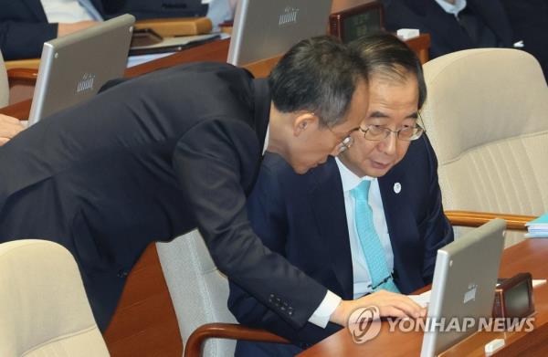 Prime Minister Han Duck-soo (R) and Finance Minister Choo Kyung-ho, who doubles as the deputy prime minister for eco<em></em>nomic affairs, discuss during an interpellation session at the Natio<em></em>nal Assembly in Seoul on Feb. 7, 2023. (Yonhap)