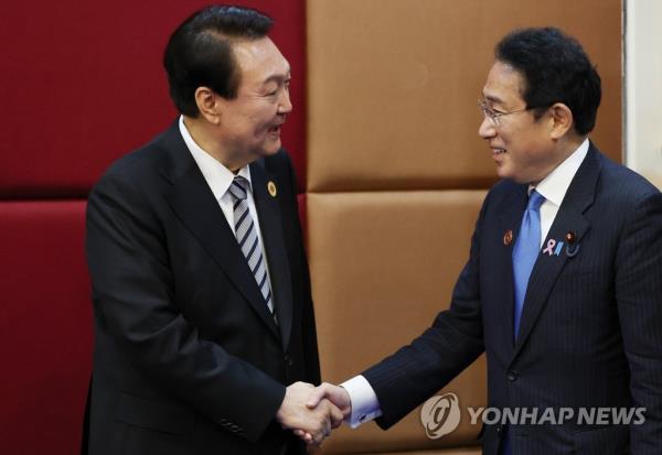 South Korean President Yoon Suk Yeol (L) shakes hands with Japanese Prime Minister Fumio Kishida during their summit at a hotel in Phnom Penh, in this Nov. 13, 2022, file photo. (Yonhap)