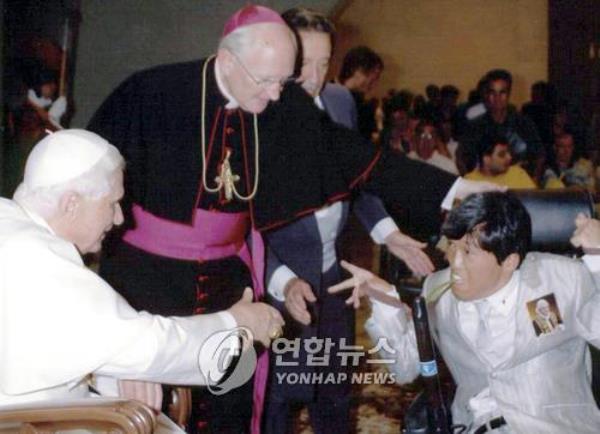 This file photo taken on July 10, 2007, shows Pope Benedict XVI (L) speaking to Choi Chang-hyeon, a handicapped South Korean who was on a tour of Europe in his motorized wheelchair, during a papal audience at the Vatican. (Yonhap)