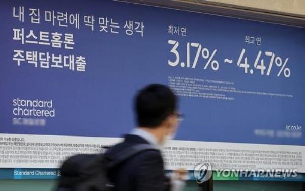 This undated file photo shows a pedestrian walking past a bulletin board in Seoul that promotes mortgage loans. (Yonhap)