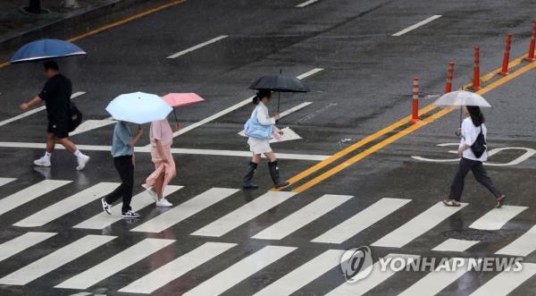 This file photo, taken July 14, 2023, shows people with umbrellas walking across a crosswalk in Gwangju, 267 kilometers south of Seoul. (Yonhap)