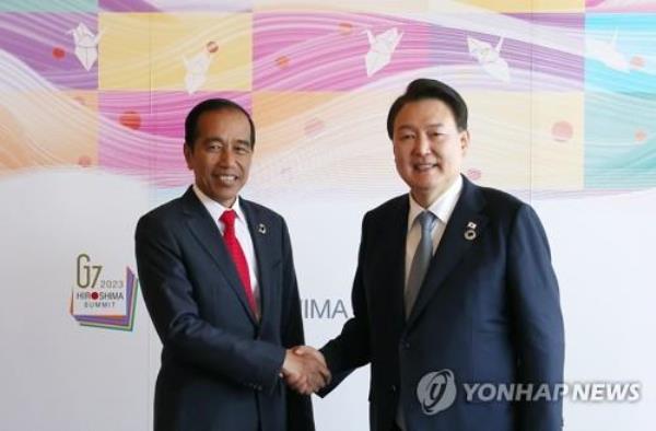 In this May 21, 2023, file photo, South Korean President Yoon Suk Yeol (R) and Indo<em></em>nesian President Joko Widodo shake hands ahead of a summit in Hiroshima, Japan, on May 21, 2023. (Pool photo) (Yonhap)