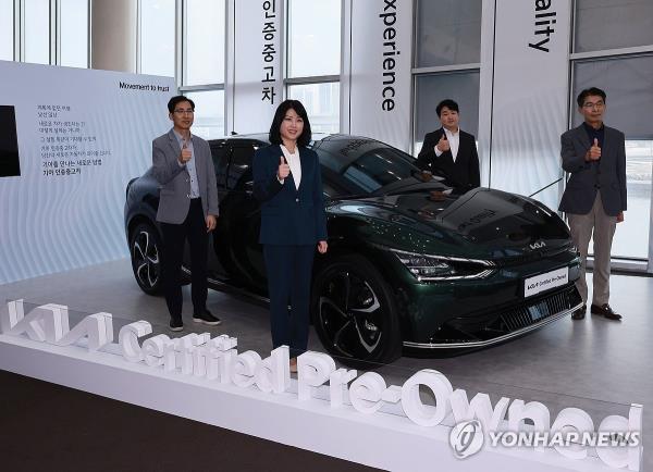 Executives at Kia Corp. pose for photos in front of a seco<em></em>ndhand Kia vehicle that has been refurbished for sale at a media event in Seoul on Oct. 25, 2023. (Yonhap)