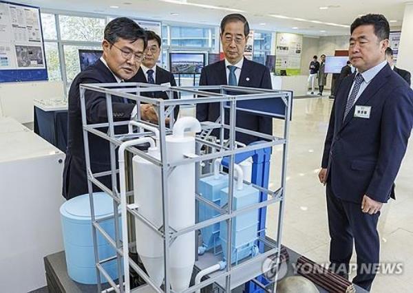 Prime Minister Han Duck-soo (C) listens to an official explaining technology to produce clean methanol before attending the presidential committee on carbon neutrality meeting in Seoul on Nov. 23, 2023. (Yonhap)