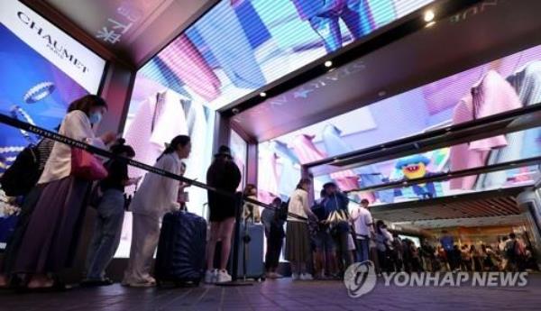 This file photo shows foreign tourists line up to enter a duty-free shop in Seoul on Aug. 11, 2023. (Yonhap)